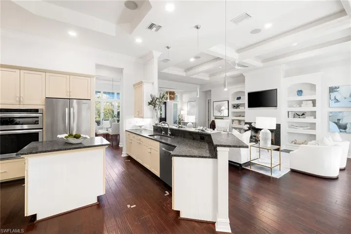 Kitchen featuring open floor plan, dark stone countertops, appliances with stainless steel finishes, a kitchen island, and hanging light fixtures