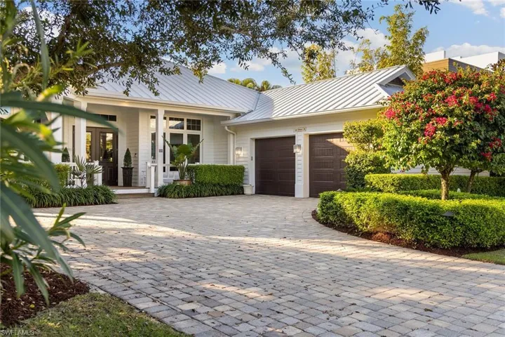 Ranch-style home featuring decorative driveway, a metal roof, a garage, and covered porch