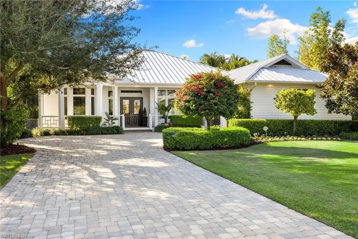 View of front facade featuring a metal roof, french doors, a porch, and decorative driveway