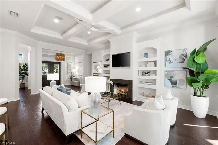 Living area featuring coffered ceiling, a premium fireplace, beamed ceiling, ornamental molding, and dark wood-style floors