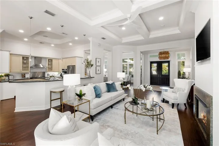Living area with crown molding, coffered ceiling, a fireplace, beam ceiling, and dark wood-type flooring