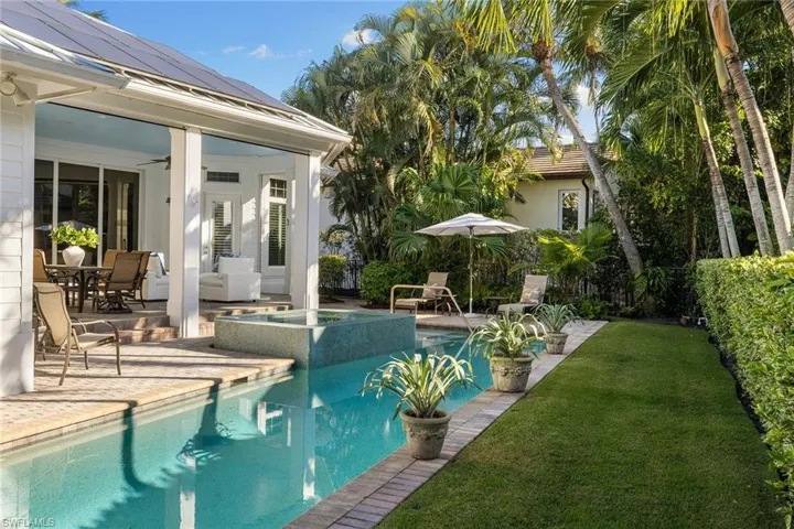 View of pool with outdoor dining area, a patio, a yard, and a pool with connected hot tub