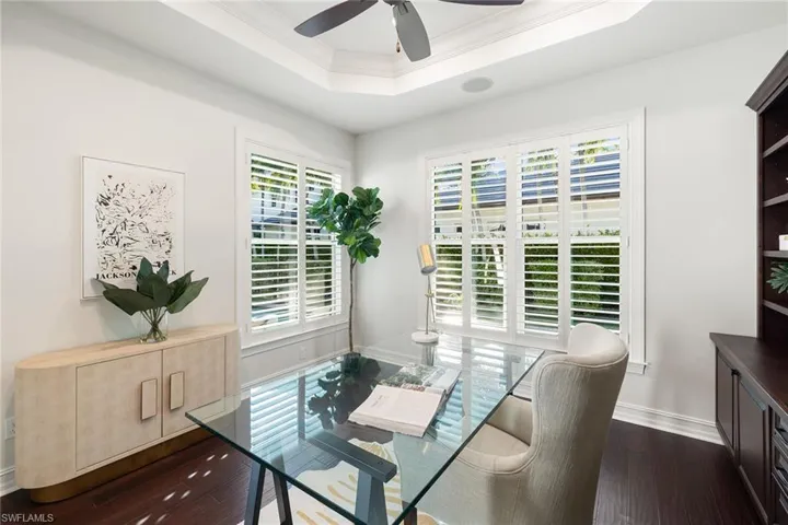 Dining area featuring ornamental molding, dark wood-style flooring, a tray ceiling, an office area, and ceiling fan