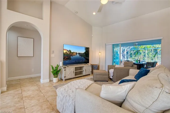 Living area featuring high vaulted ceiling, a ceiling fan, arched walkways, tile patterned floors, and recessed lighting