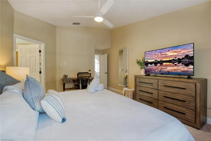 Bedroom featuring vaulted ceiling, ceiling fan, and light carpet
