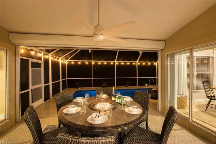 Patio at night with outdoor dining space, a sunroom, an outdoor pool, and a patio area
