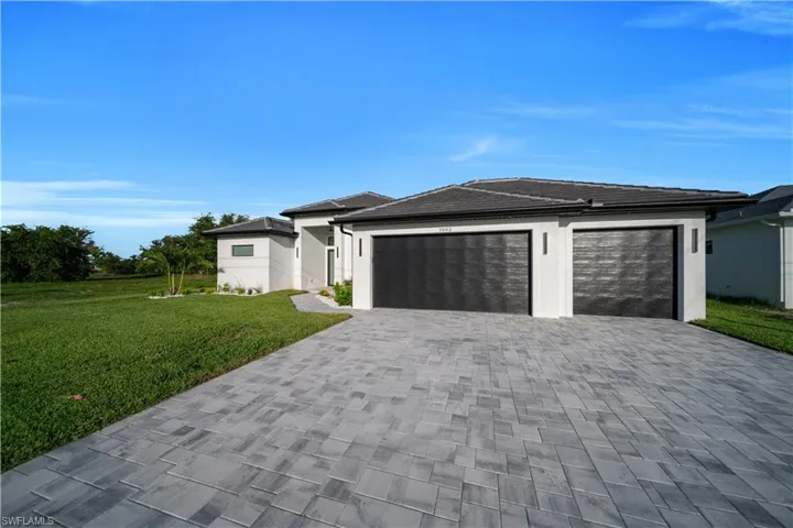 View of front facade featuring decorative driveway, a garage, a front yard, and stucco siding