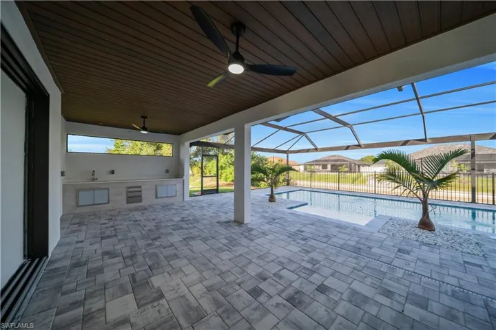 View of patio with exterior kitchen, a ceiling fan, and glass enclosure