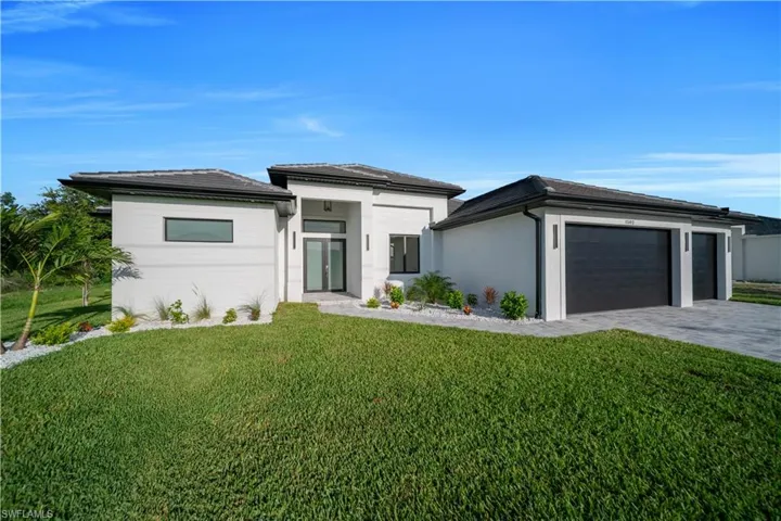 Prairie-style house with an attached garage, decorative driveway, a front lawn, and stucco siding