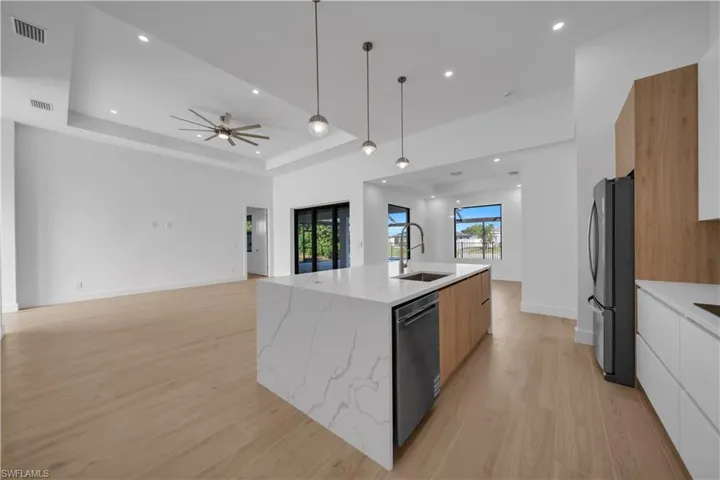 Kitchen with modern cabinets, appliances with stainless steel finishes, light wood-type flooring, a center island with sink, and recessed lighting