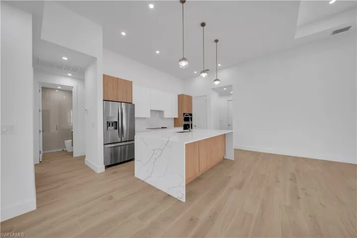 Kitchen featuring stainless steel fridge, modern cabinets, light wood-style floors, pendant lighting, and recessed lighting