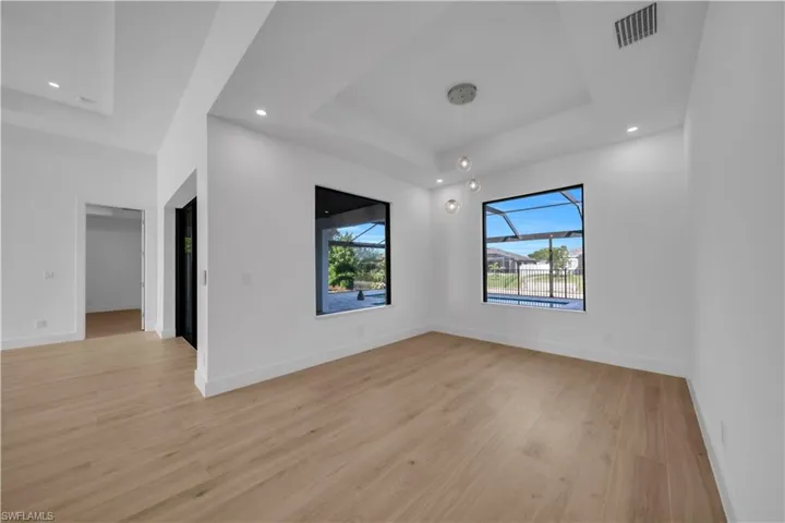 Unfurnished room with a raised ceiling, light wood-type flooring, and recessed lighting