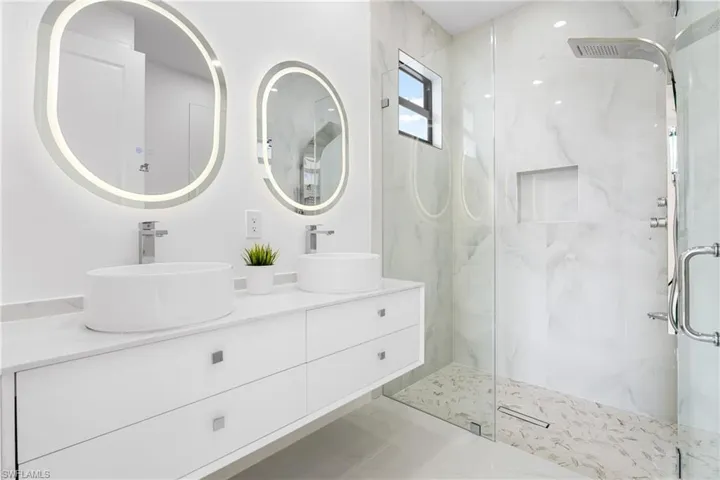 Bathroom with double vanity and a marble finish shower