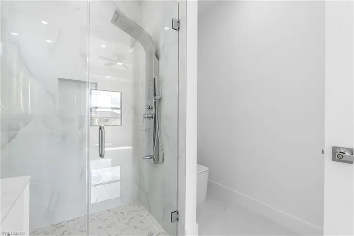 Full bathroom featuring a marble finish shower and light marble finish floors