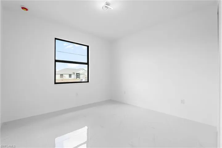Spare room featuring light marble finish flooring and baseboards