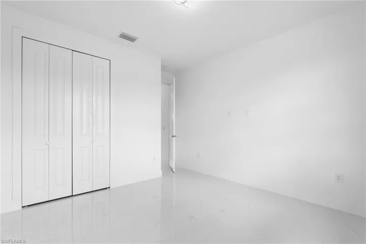 Unfurnished bedroom featuring light marble finish floors and a closet