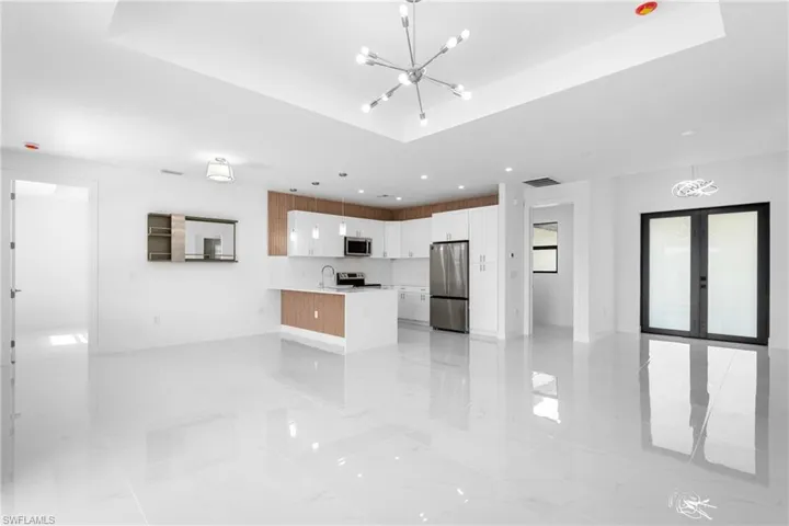 Kitchen with a chandelier, open floor plan, stainless steel appliances, white cabinets, and a peninsula