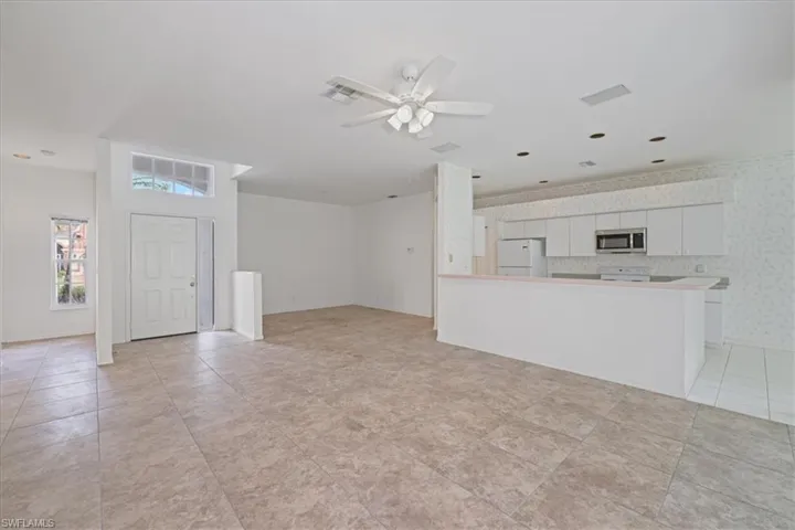 Unfurnished living room featuring wallpapered walls and a ceiling fan