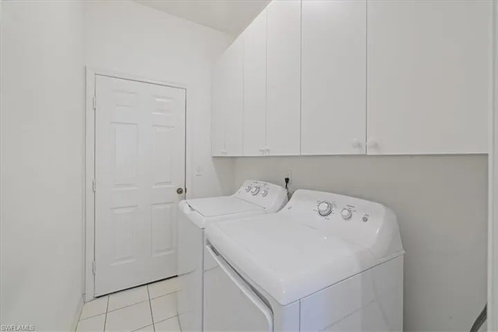 Laundry room with light tile patterned floors, cabinet space, and washer and clothes dryer