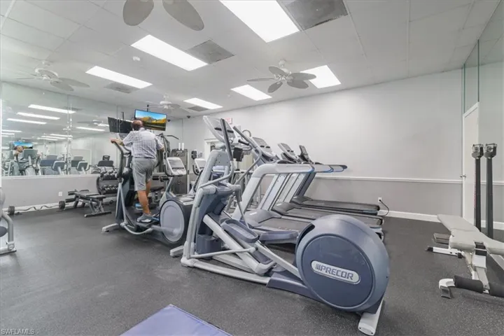 Gym with a ceiling fan and a drop ceiling