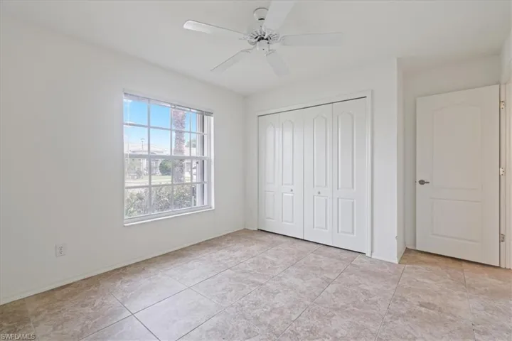 Unfurnished bedroom with a ceiling fan, a closet, and light tile patterned floors