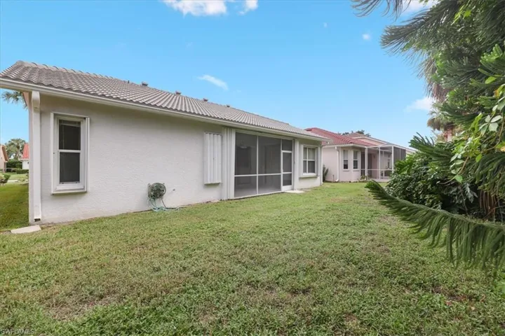 Back of property featuring a lawn, stucco siding, and a sunroom