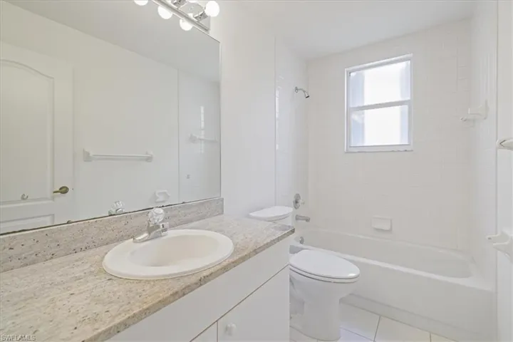 Full bath featuring bathing tub / shower combination, vanity, and light tile patterned floors