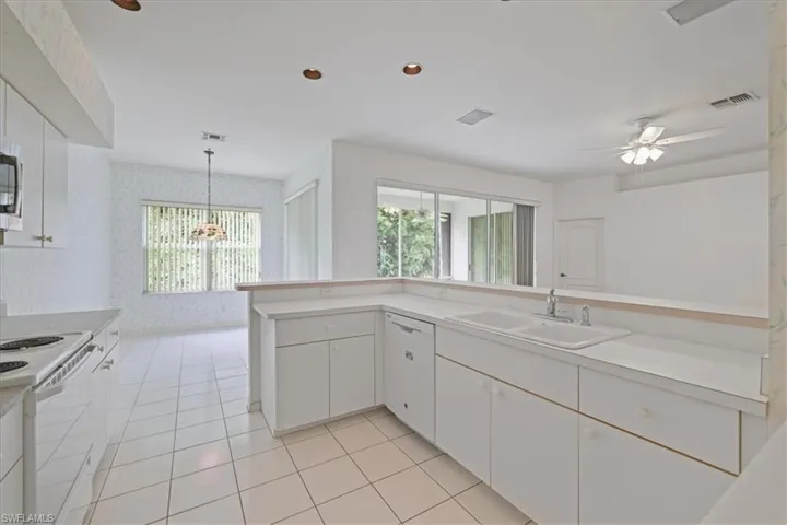 Kitchen with white cabinetry, white appliances, healthy amount of natural light, wallpapered walls, and recessed lighting