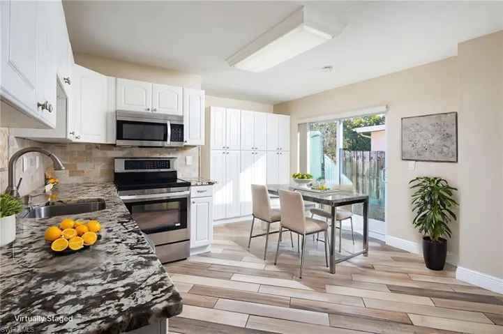 Kitchen with granite countertops, stainless steel appliances, white cabinets, large pantry and wood plank tile flooring. New slider door with access to side yard.