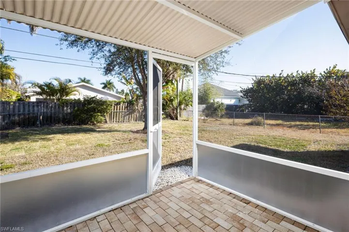 View of fenced back yard from screened-in sunroom/lanai.