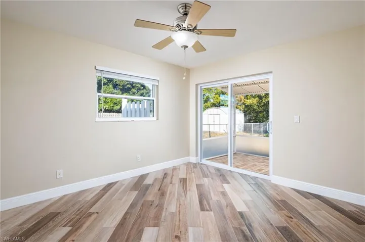 Bedroom/Office/Den with multiple windows, wood plank tile floors, ceiling fan, and newly-installed slider glass door with access to outside lanai and back yard,