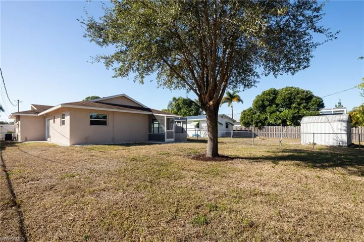 Rear view of house featuring a fenced backyard, stucco siding, and sunroom.