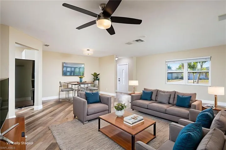 Living area with wood plank tile flooring. View towards front entry.  New fan and light fixture. Freshly painted.