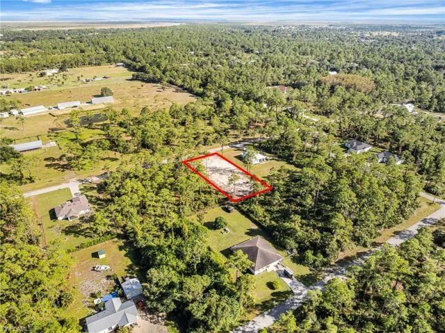 Aerial view of property and surrounding area featuring property parcel outlined and a forest