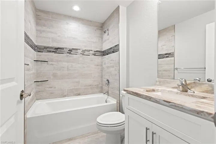 Full bathroom with hardwood / wood-style floors, vanity, toilet, and tiled shower / bath