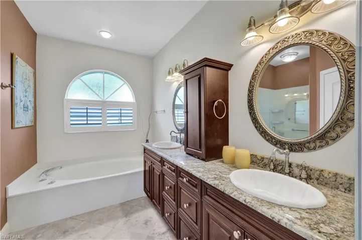 Bathroom with a bath, double vanity, and a sink