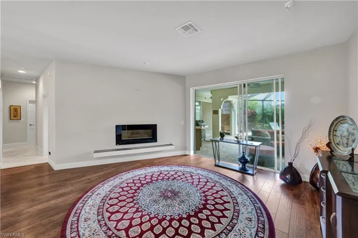 Living area featuring a glass covered fireplace, visible vents, wood finished floors, and baseboards