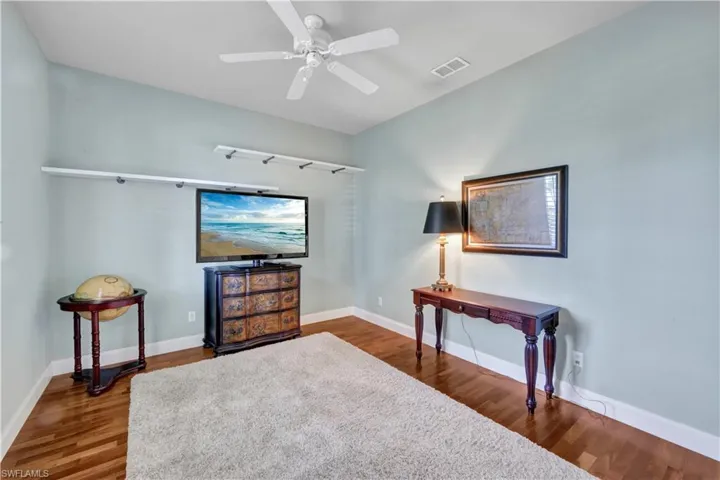 Living area with baseboards, visible vents, wood finished floors, and a ceiling fan