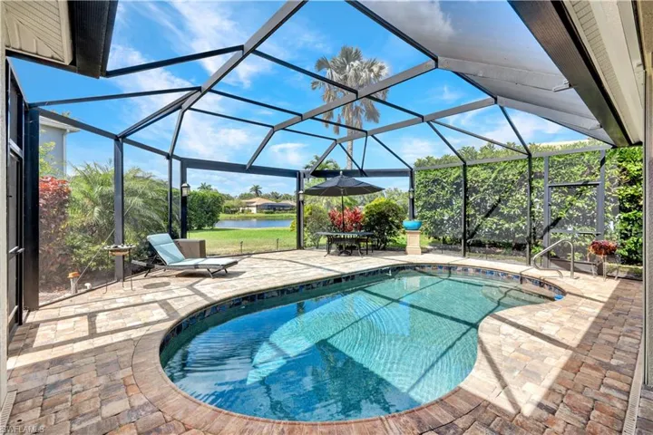 Pool featuring a water view, a patio, and glass enclosure