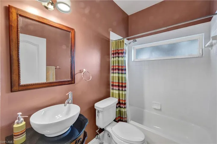 Full bath with shower / tub combo with curtain, toilet, and a sink