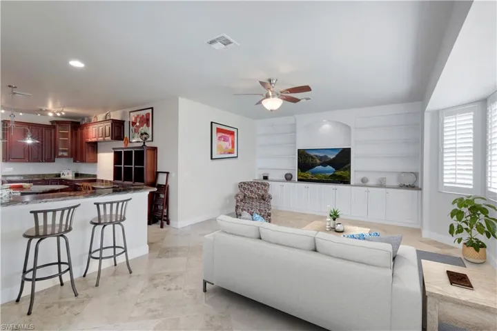 Living room with visible vents, a ceiling fan, built in features, and baseboards