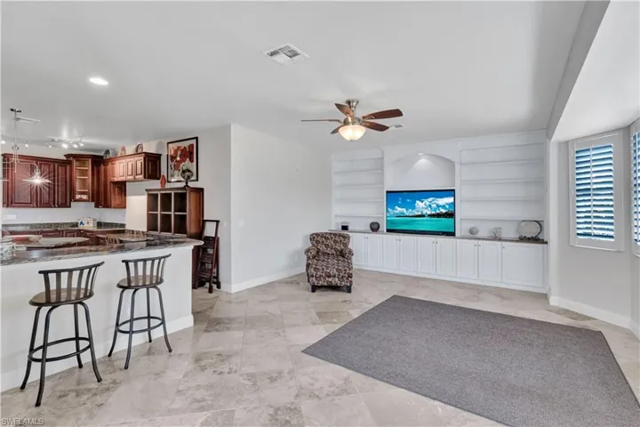 Living area featuring a ceiling fan, visible vents, built in features, and baseboards