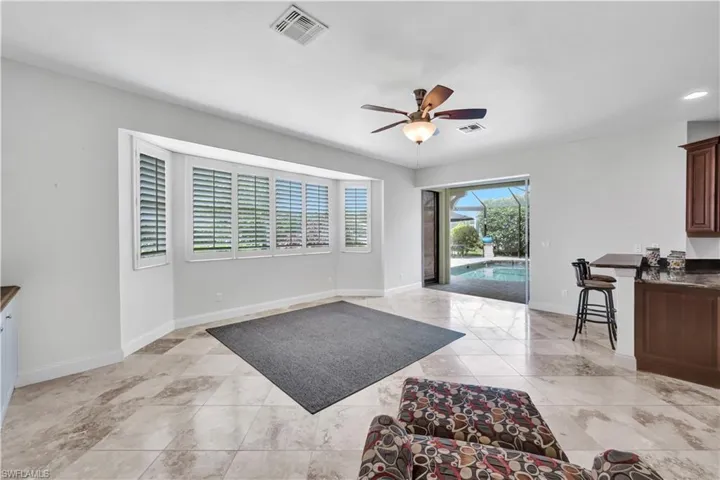 Living area featuring light tile patterned flooring, visible vents, ceiling fan, and baseboards
