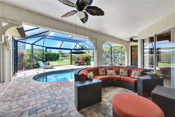 Pool featuring an outdoor living space, a water view, glass enclosure, a patio area, and a ceiling fan