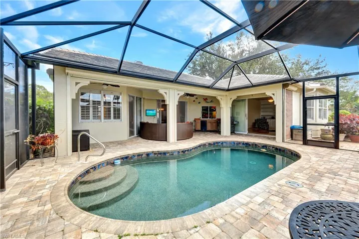 Outdoor pool featuring ceiling fan, glass enclosure, and a patio area