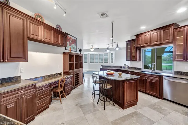 Kitchen with stainless steel dishwasher, built in desk, a sink, visible vents, and a ceiling fan