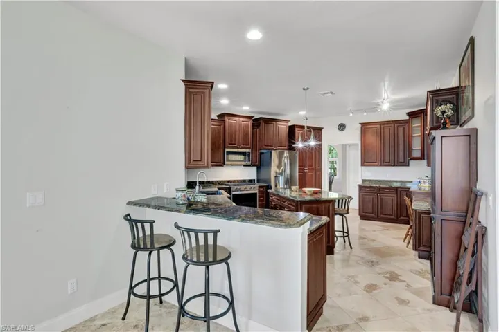Kitchen with recessed lighting, appliances with stainless steel finishes, a kitchen bar, a sink, and a peninsula