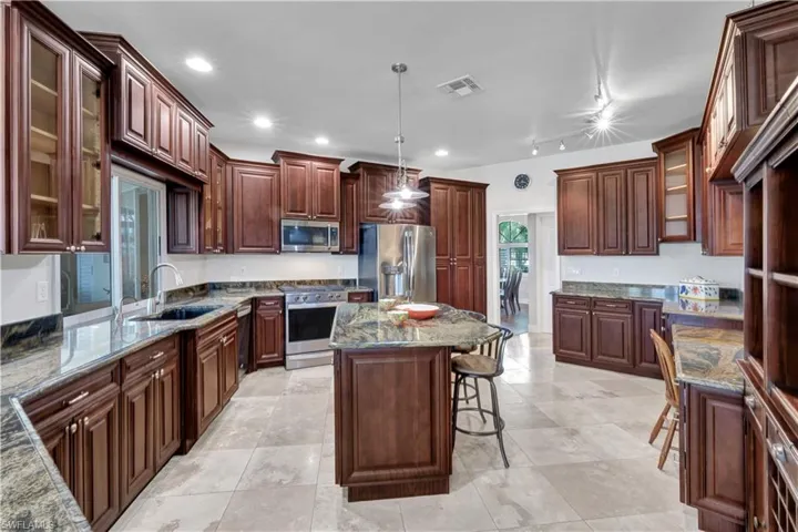 Kitchen featuring a breakfast bar area, a sink, appliances with stainless steel finishes, visible vents, and stone counters