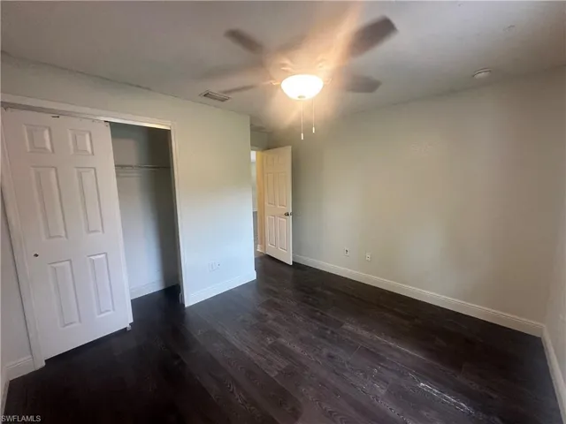 Unfurnished bedroom with dark wood-style flooring, a ceiling fan, and a closet