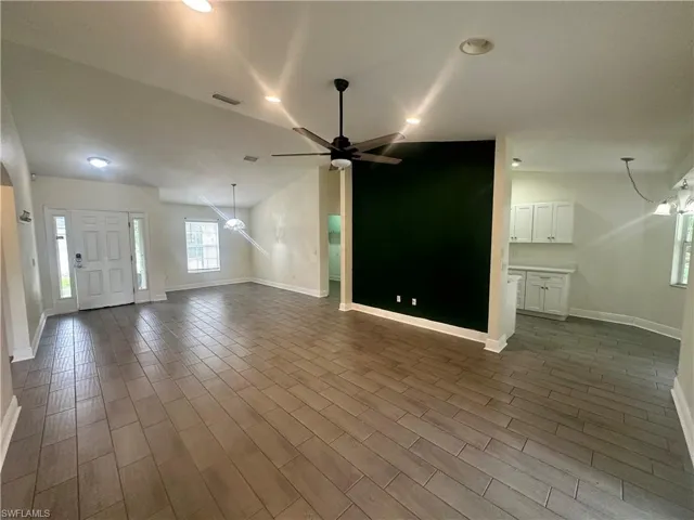 Unfurnished living room with ceiling fan, wood tiled floors, and vaulted ceiling